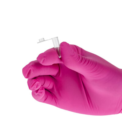 Ręka w różowej rękawiczce ochronnej trzyma małą, przezroczystą probówkę laboratoryjną.